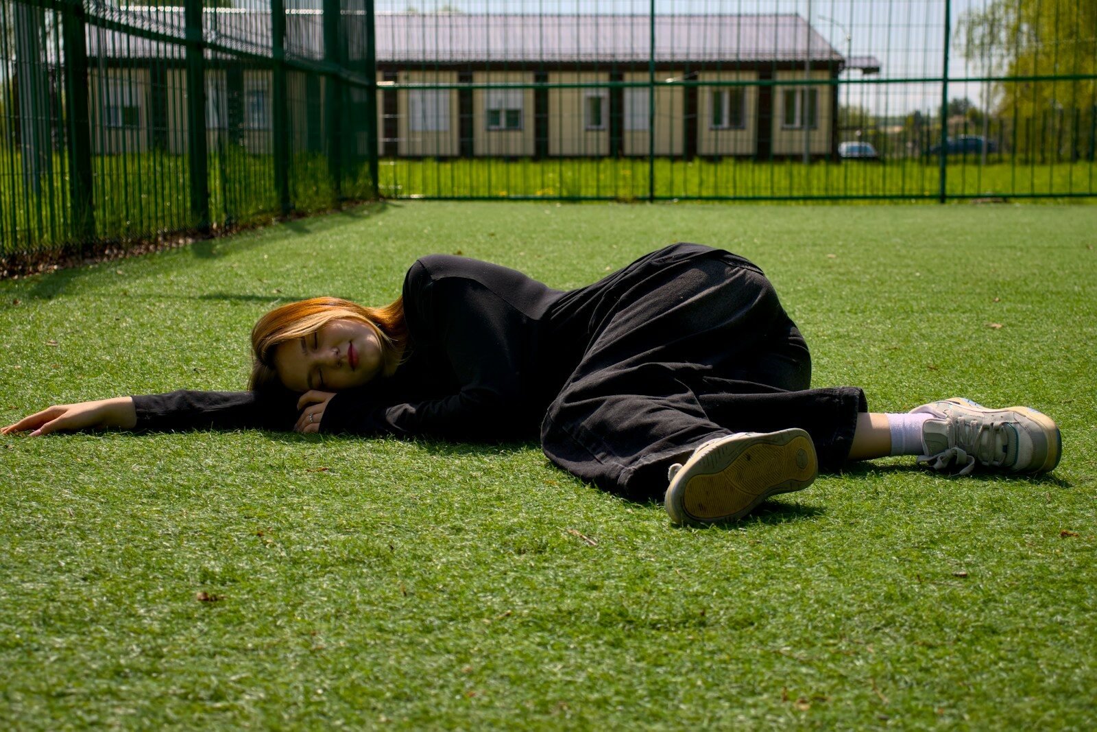 A woman is lying on the green field.